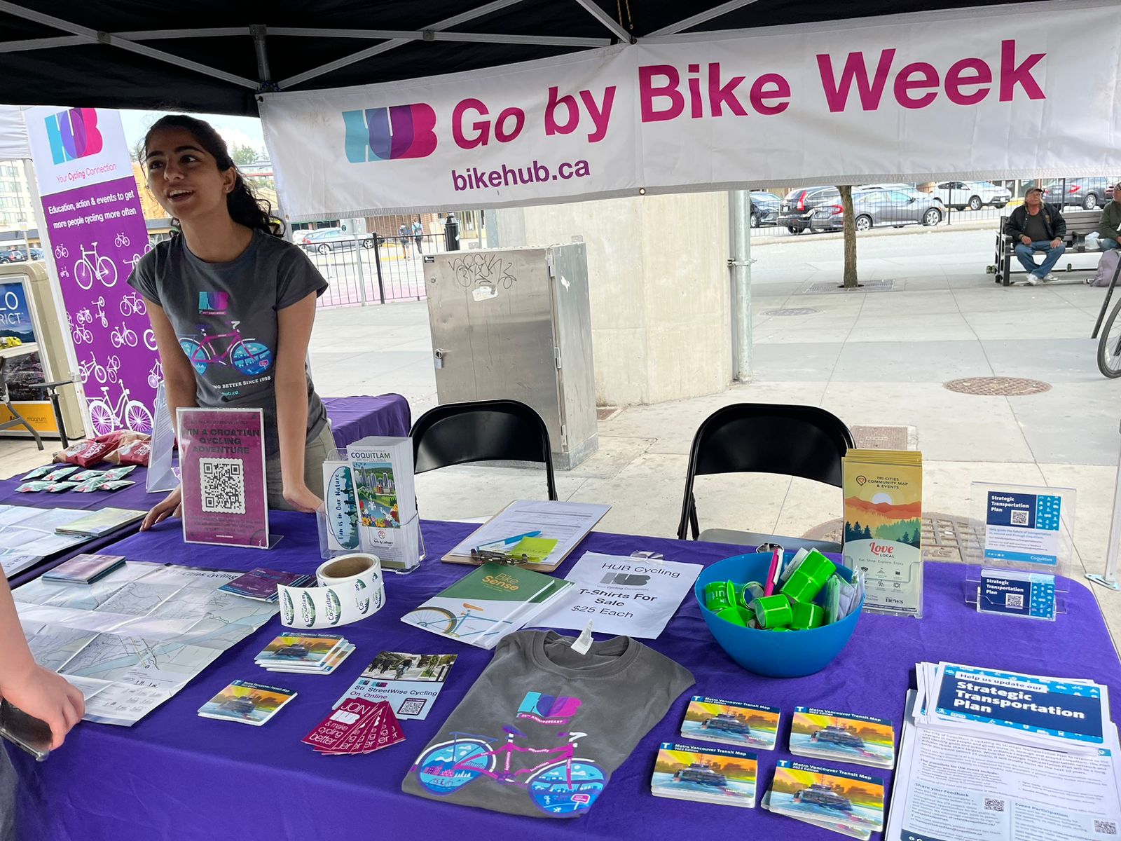 A young woman in her twenties stand behind an information booth at an event promoting safe cycling