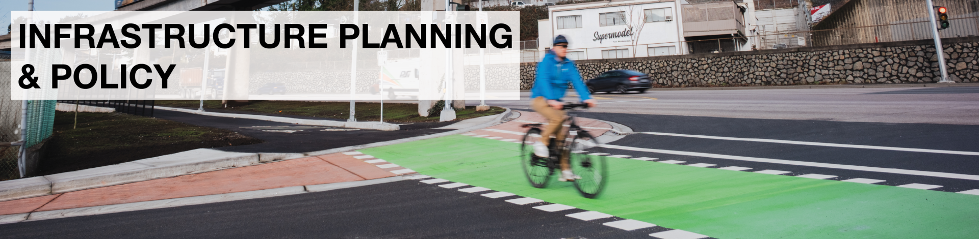 A man rides his bike across a painted green bike lane in Metro Vancouver.
