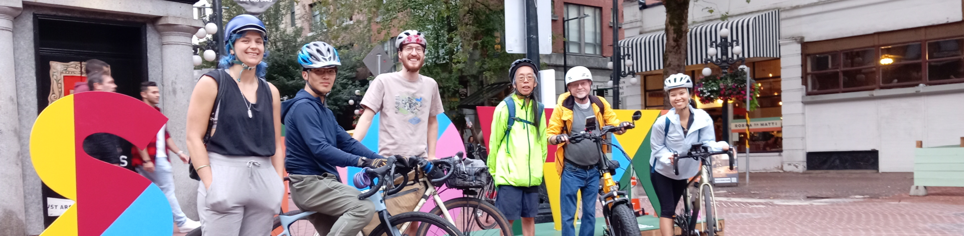 Six people pose with their bikes in Gastown.