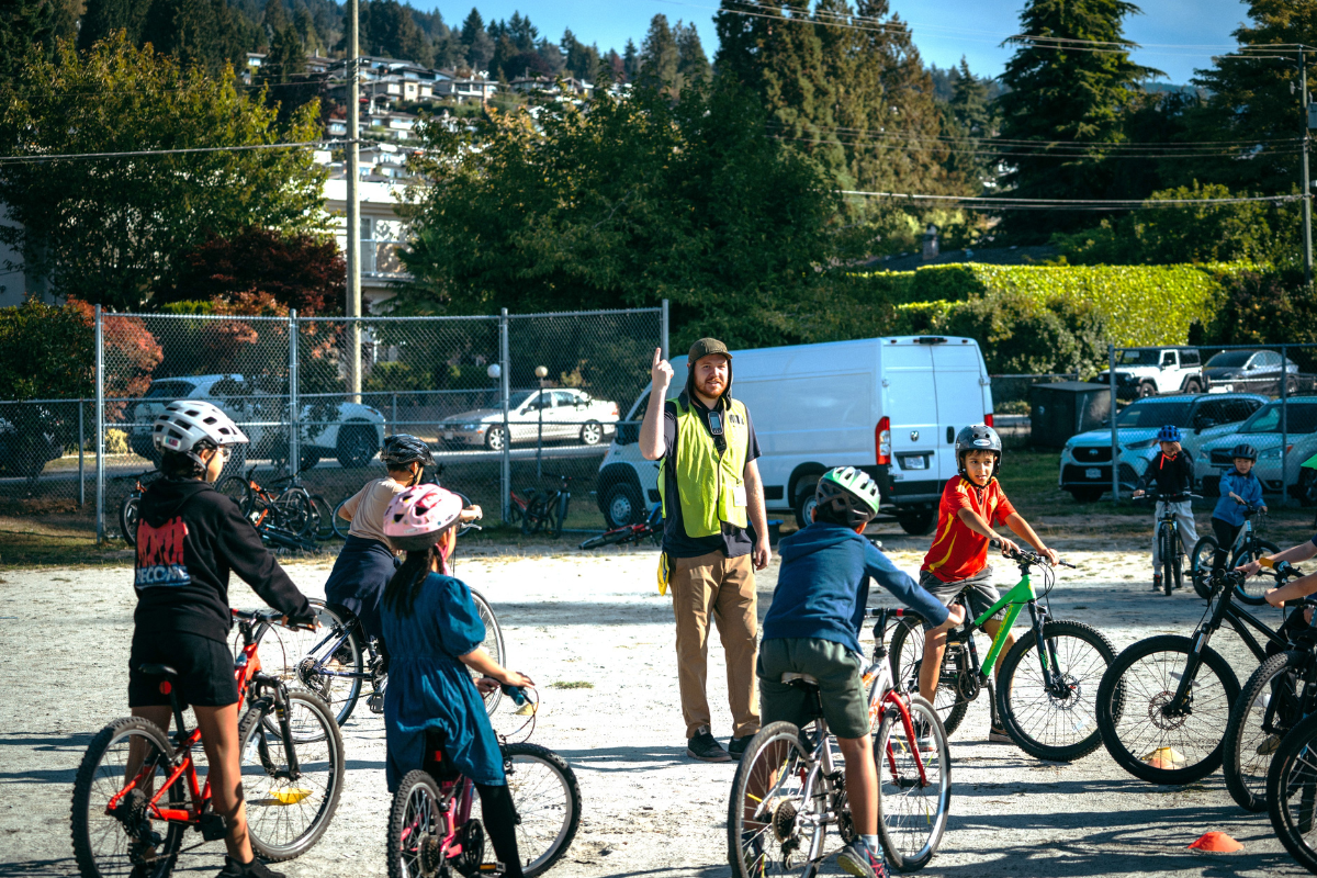 An instructor teaches kids on bikes in a schoolground.