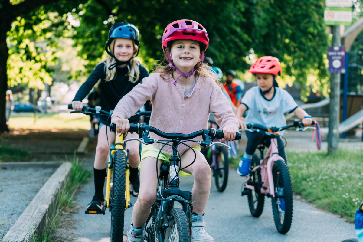 Three children ride bikes on a bike path.