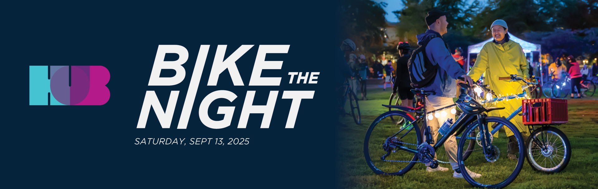 HUB Cycling Bike the Night banner, Saturday, Sept. 13, 2025. Two people stand on a grass field with their bikes while laughing.