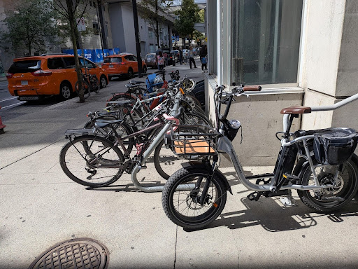 Several bikes parked in bike racks outside of a storefront.
