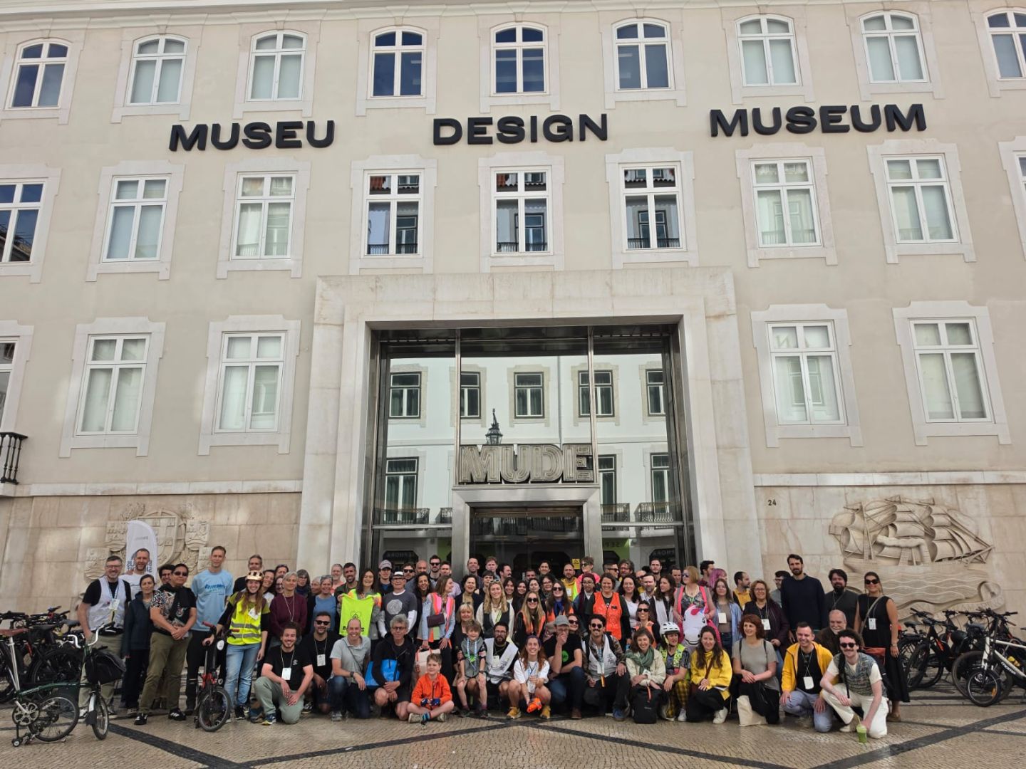 A group photo of people and their bikes in front of the Museu Design Museum.