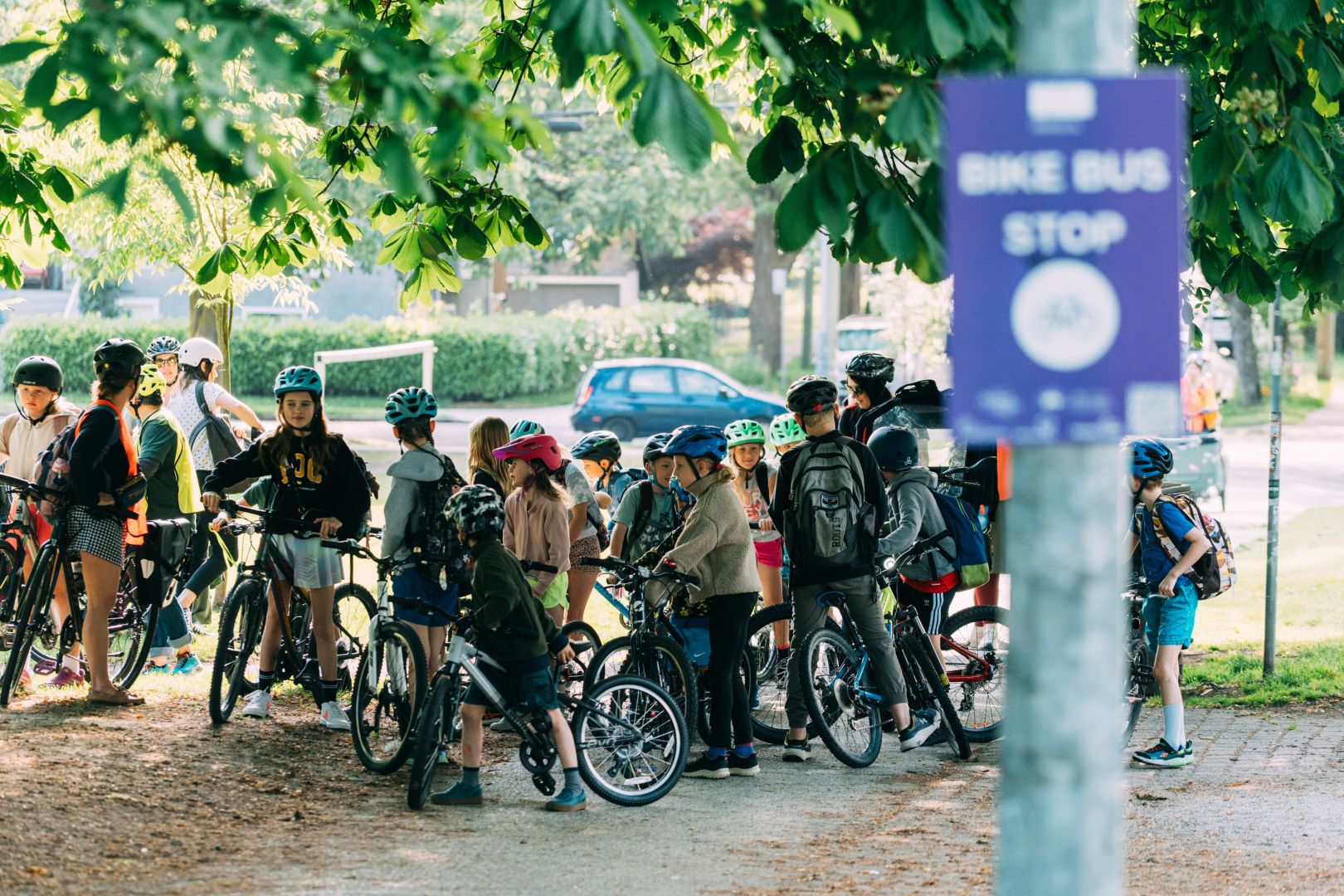 a group of kids on bikes are gathered in front of a sign for bike bus