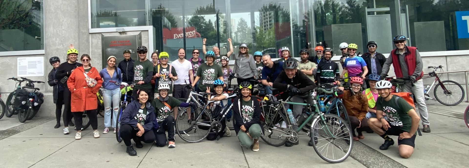 HUB Cycling staff in helmets and I Love Biking t-shirts pose for a group photo in front of the Lafarge Lake skytrain station