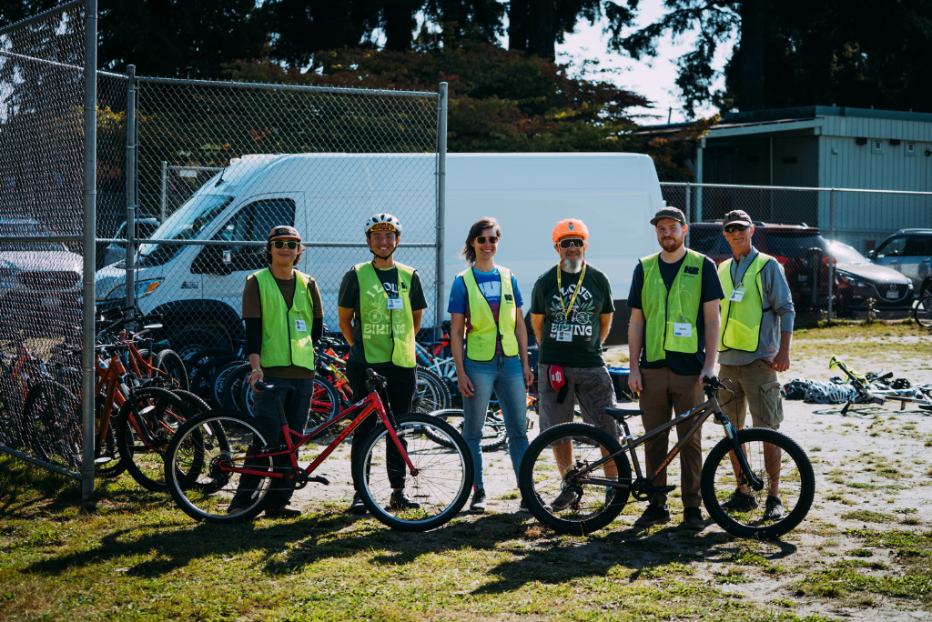 Six instructors pose for a photo wither two bikes.