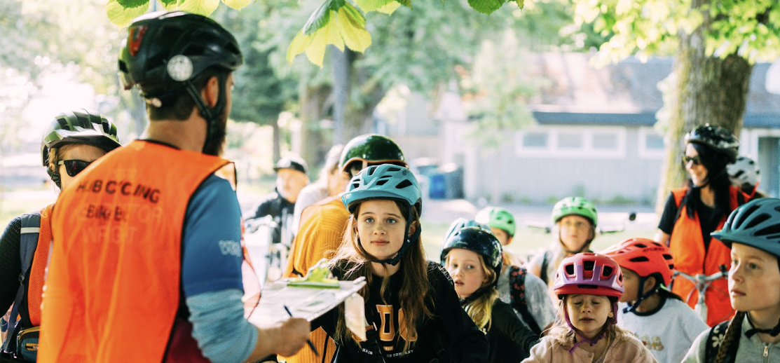 Several bike bus participants listen to the bike education instructor go over the safety instructions before their ride.