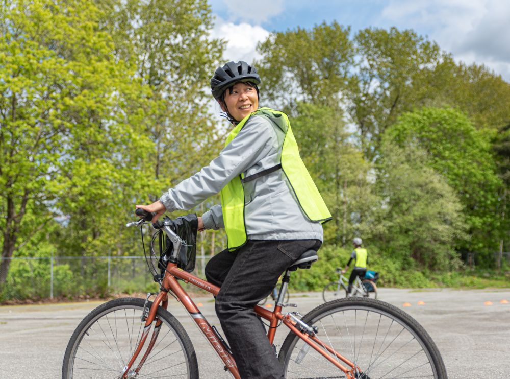 A woman rides her bike and looks back over her shoulder.