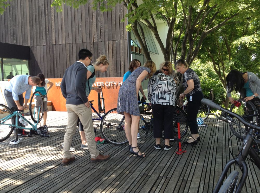 A group of people gather around to inspect a bike.
