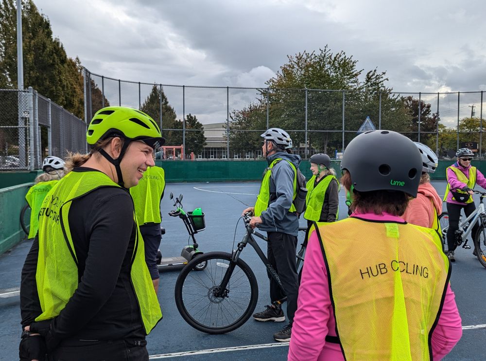 A bike education instructor speaks to a participant. People stand with their bikes in the background.