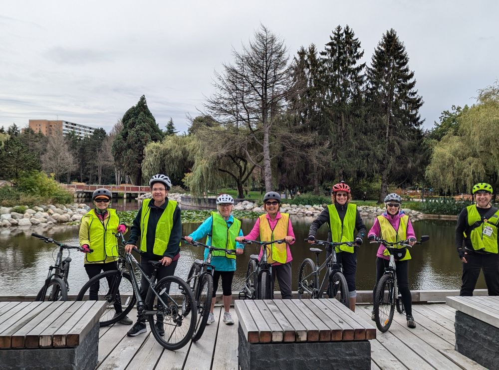 A group of people pose for a photo with their bikes on a bridge.