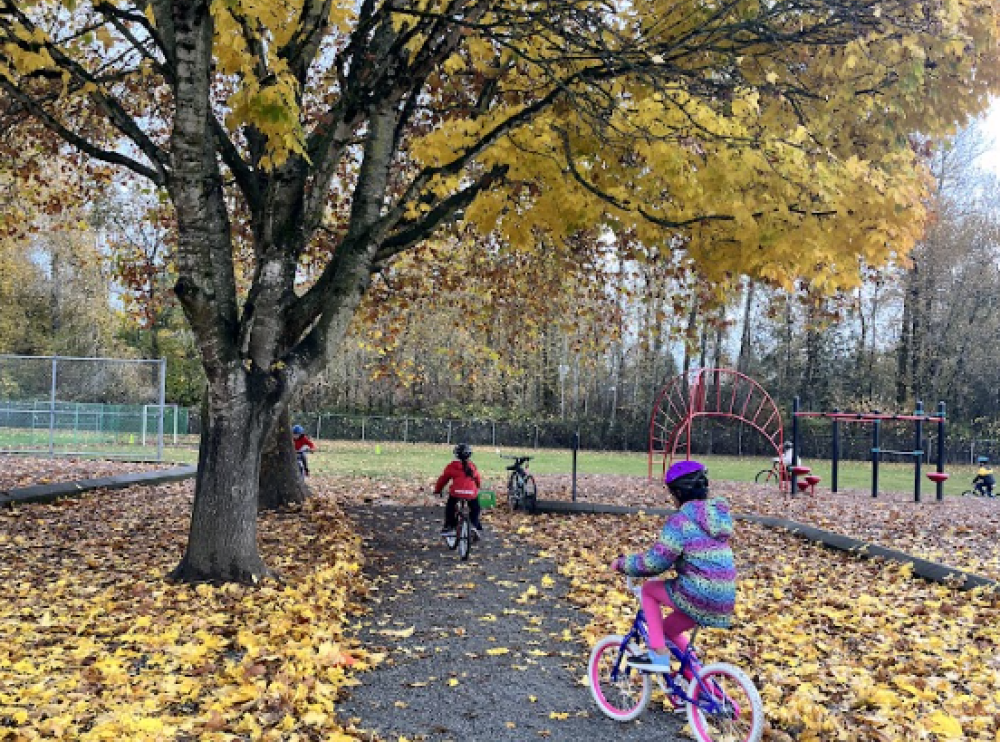 School children ride their bikes on school grounds during the fall.