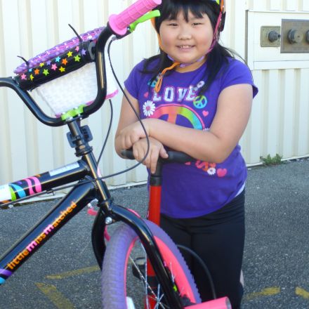 girl wearing a bike helmet leans on a bike pump next to her bike on Mechanics Day of Everyone Rides Road Skills