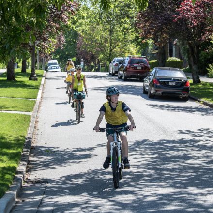 Three children and an adult instructor riding in a line on a tree lined street during an Everyone Rides Road Skills Road Ride