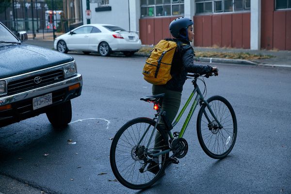 A woman crosses the road with her bike.