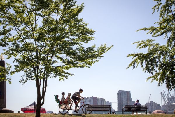 A father rides a bike with three children on the back.