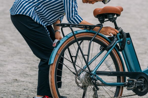 A woman bends down to inspect the back wheel of her bike.