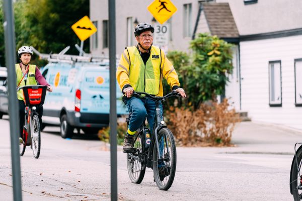 Two people ride their bikes on the road. They are both wearing yellow HUB jerseys.