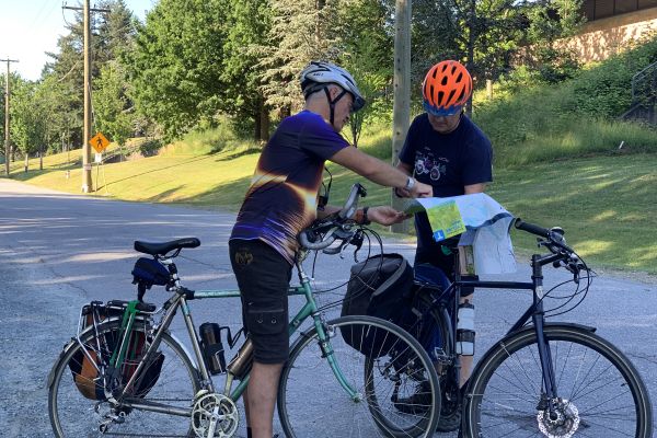 Two men with bikes look at a bike map together.