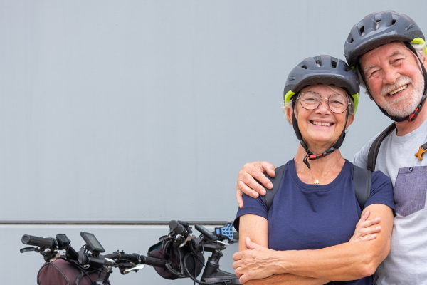 A senior couple poses with their e-bikes.