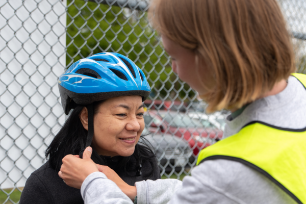 An instructor helps tighten a women's helmet.