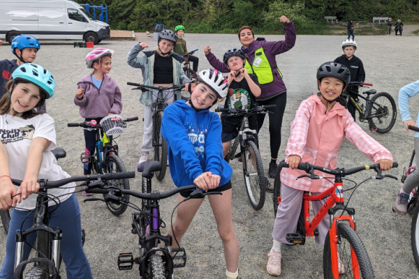 Students pose for a silly photo with bikes on a gravel field.