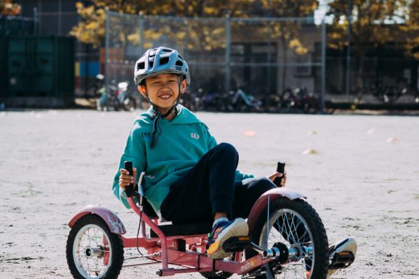 A boy rides an adaptive bike on school grounds.
