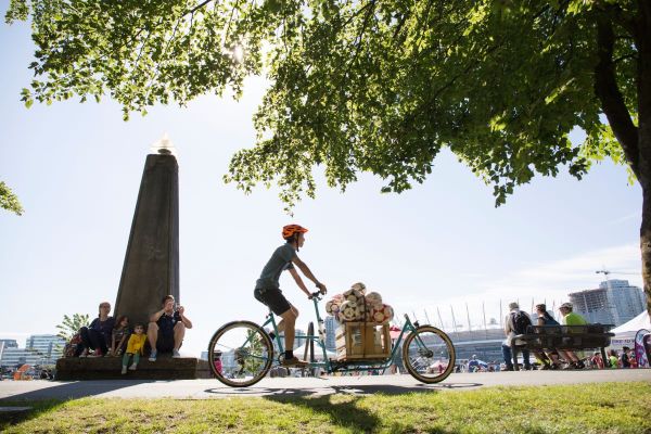 A young man rides a cargo bike along the Seawall carrying soccer balls.
