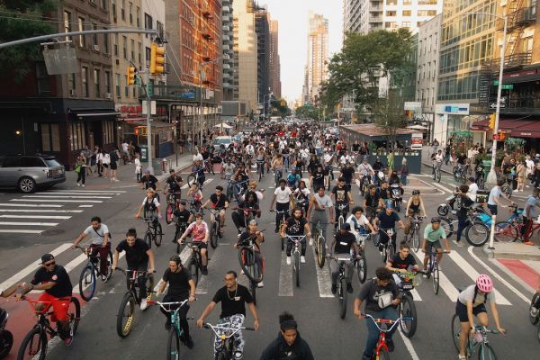 A group of people ride their bikes in mass down a city street.
