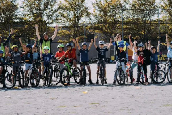 Students and teachers line up with their bikes for a group photo on school grounds.