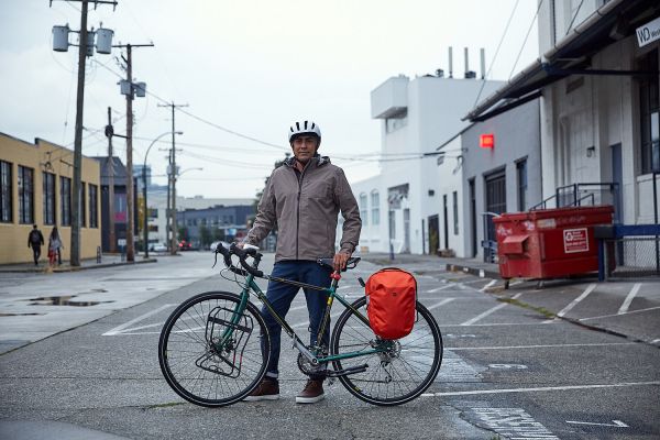 A man stands with his bike on a quiet road.