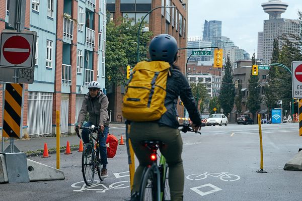 Two people ride their bikes in downtown Vancouver.