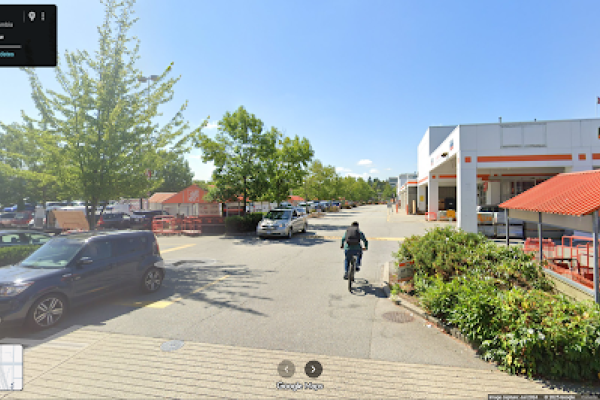 A rider bikes into the entrance of a Home Depot parking lot.