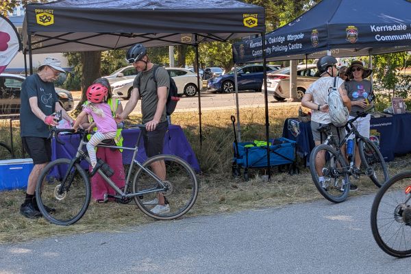 Several people gather around pop-up tents to register their bikes with Project 529 during HUB Cycling's bike parking summer pop-ups.