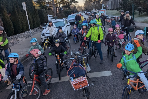 Students, parents, and instructors ride bikes in a bike bus.