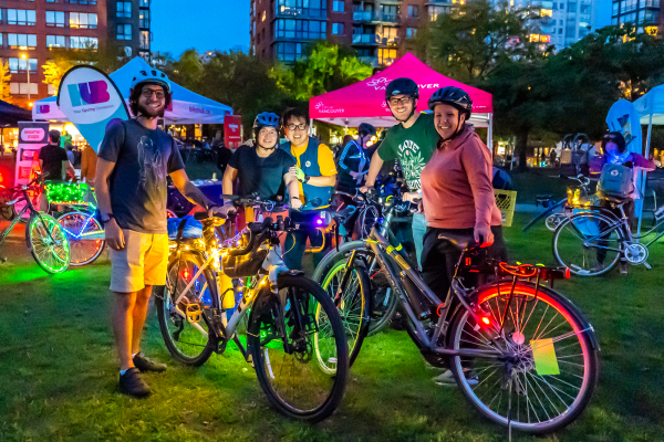 A group of people stand beside brightly lit bikes