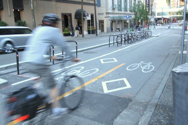 A man rides his bike in downtown Vancouver on a two-way cycle track.
