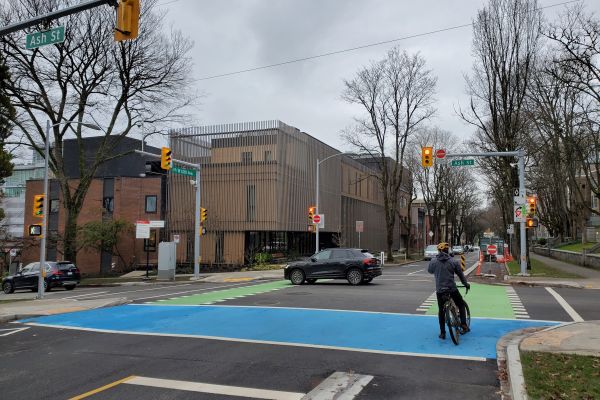person on bike waiting at intersection with blue conflict paint to indicate cycling usage