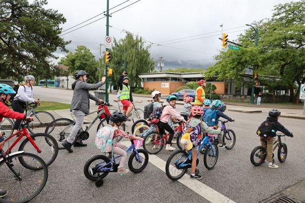 A group of students ride on the road in an organized 'bike bus.'