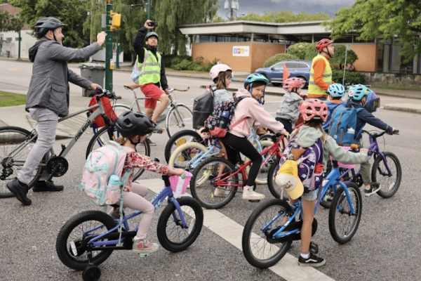 Several students, parents, and teachers ride their bikes in a 'bike bus'.