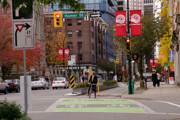 Photo credit: Paul Krueger. A woman rides her bike in downtown Vancouver.