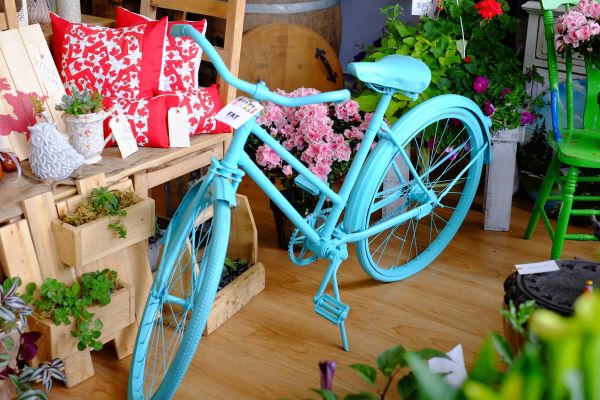 A painted blue bike surrounded by flowers