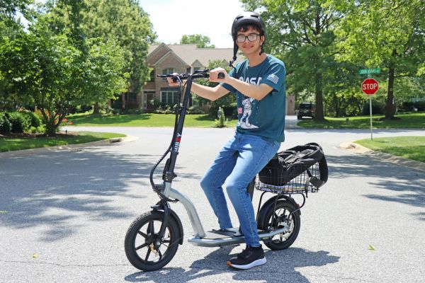 A teen boy sits on an electric assist bike.