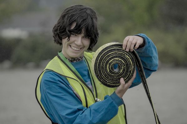 A bike education instructor smiles as she holds a roll of turf used to set up obstacles for a cycling course.