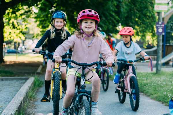 Three children ride their bikes on a bike path.
