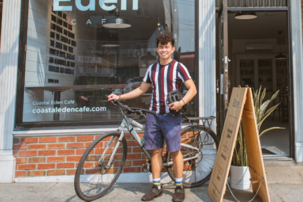 person standing with bike in front of coffee shop