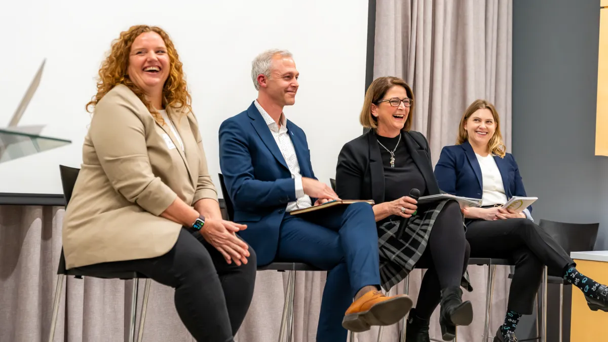 Four people laugh together as they sit on a panel.