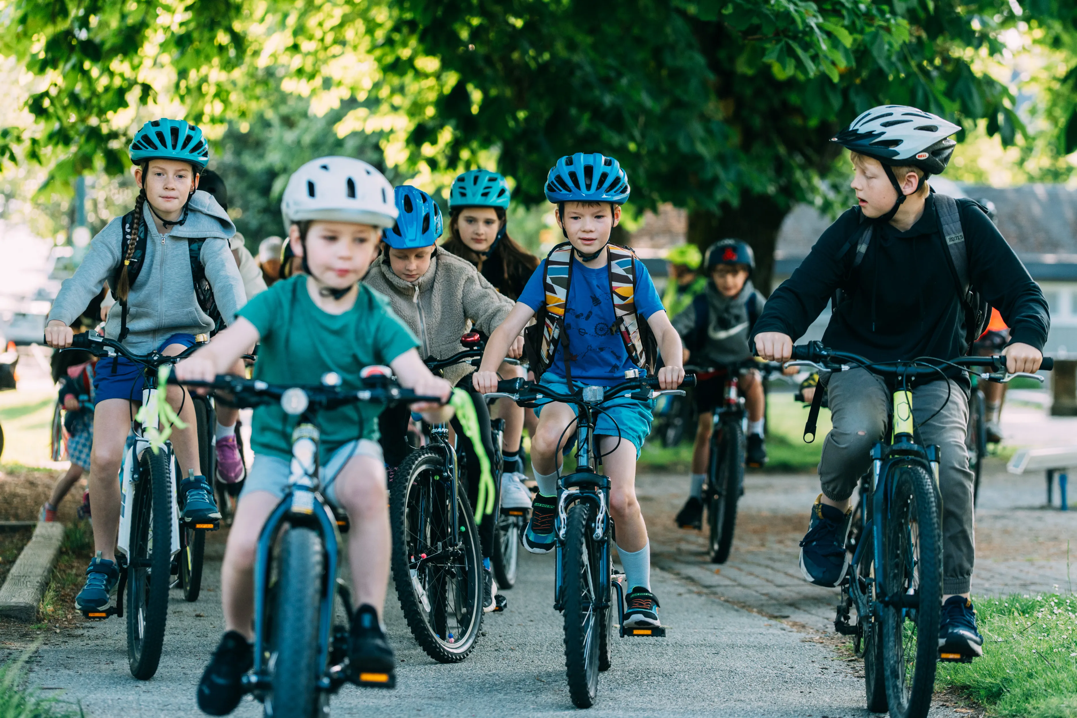 A group of children ride bikes on a bike path.