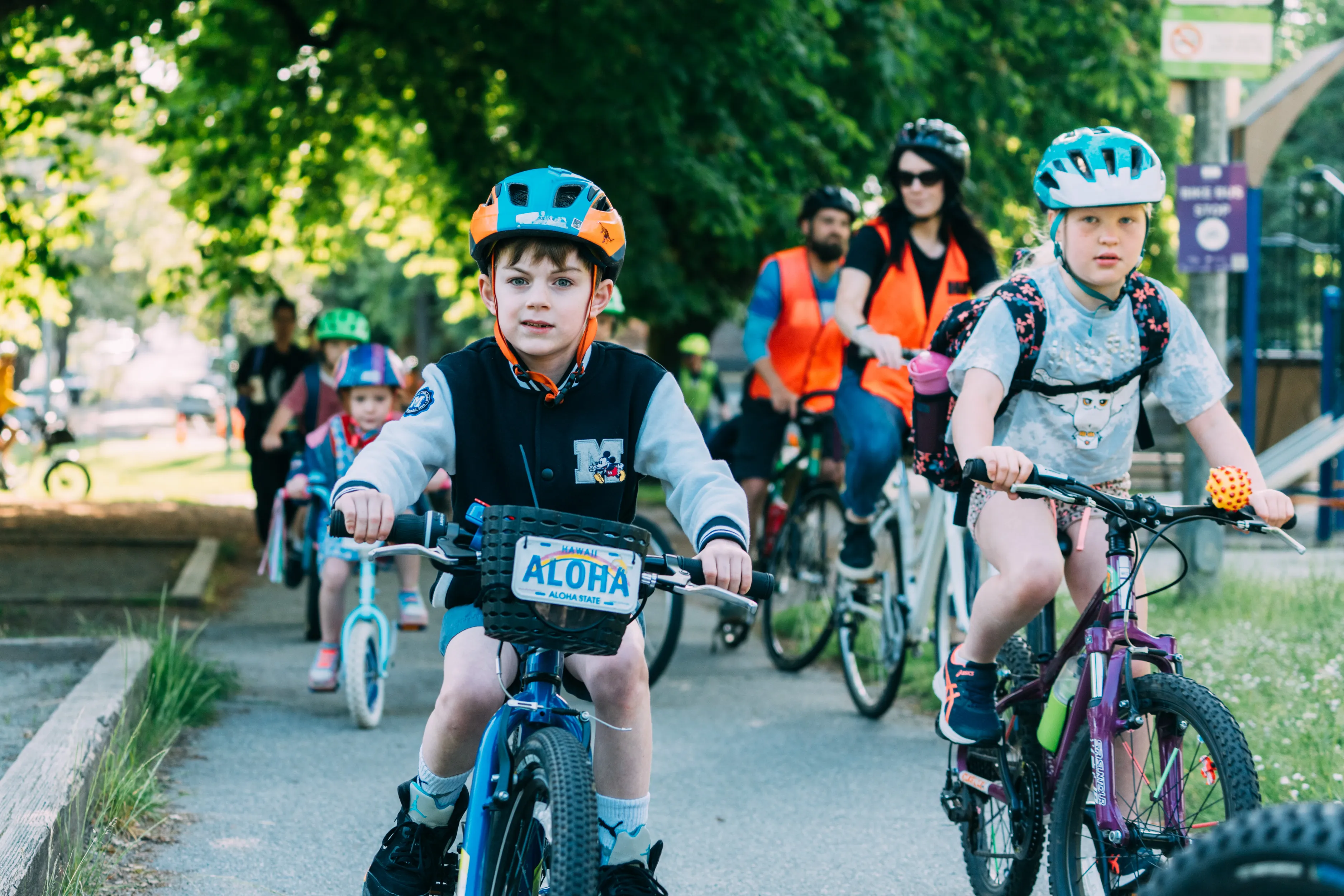 A group of school children ride bikes on a bike path.
